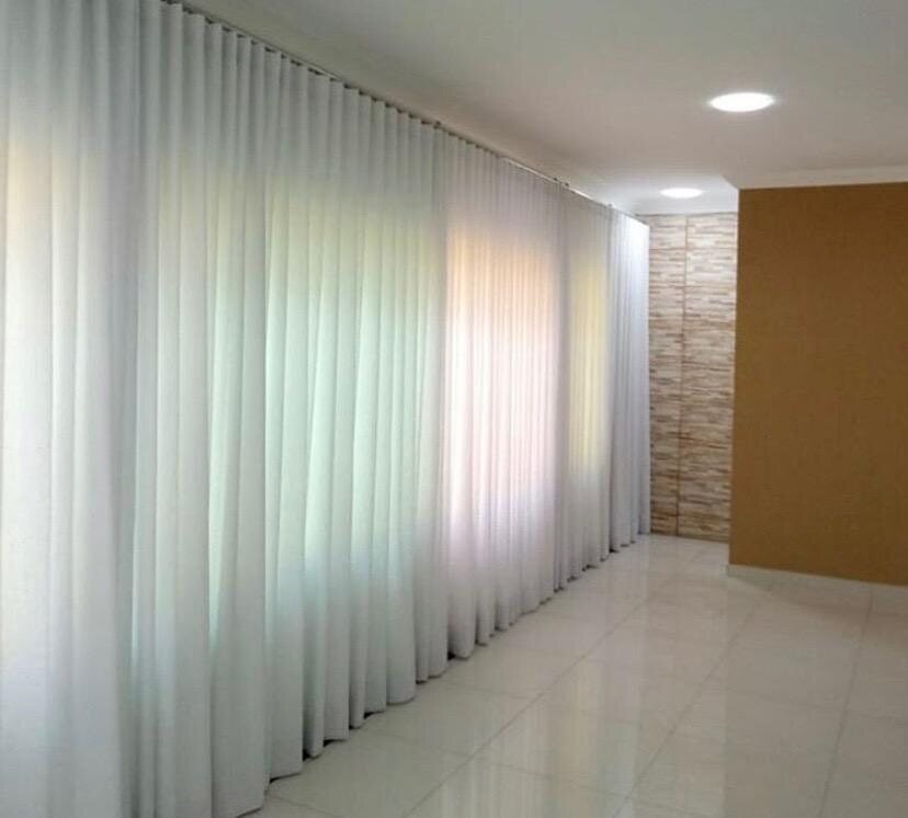 Cortinas brancas sob medida cobrindo parede de vidro em corredor