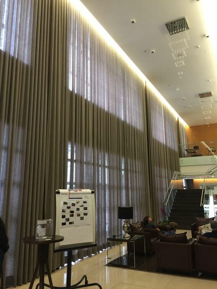 Cortinas de tecido em pé direito duplo instaladas em hall corporativo